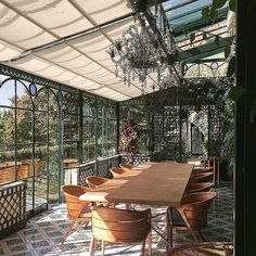 an outdoor dining area with tables and chairs, surrounded by greenery in the background