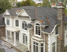 an aerial view of a large house with stone and shingles on it's roof