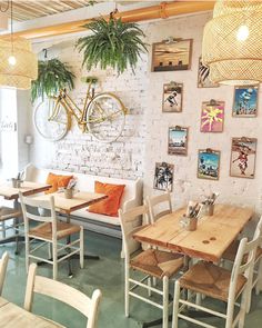 the interior of a restaurant with tables, chairs and plants hanging on the wall above them