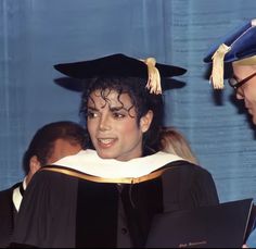 a woman in a graduation cap and gown is talking to another person with a book