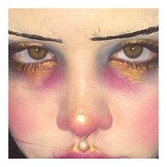 a close up of a woman's face with bright makeup and gold eyeshadow