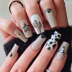 Cowgirl inspired nails evoke a rustic yet chic vibe reminiscent of the Wild West. Imagine cow print designs, horseshoes, cacti, or even miniature cowboy hates for added flair. It's a whole rodeo and we want the entire look. Black And Gold Cow Print Nails, Western Print Nails, Current Nail Designs, Black Western Nail Designs, Almond Shape Western Nails, Cowprint Nail Design Almond, Fall Cowgirl Nails, Western New Years Nails, Rodeo Nails Designs Westerns