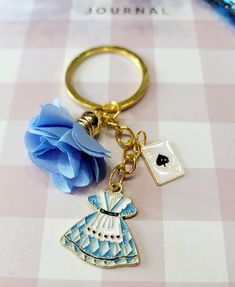 a keychain with a blue rose on it and a card in the shape of a dress