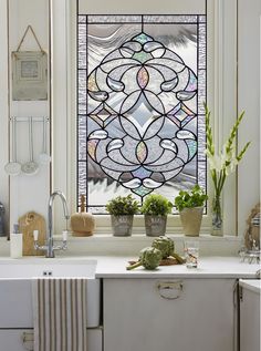 a kitchen window with potted plants in front of it