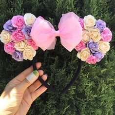 someone is holding up a pink and purple minnie mouse ears headband with flowers on it