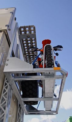 a bicycle is strapped to the side of a metal structure in front of a blue sky