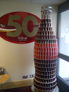 a large stack of cans sitting in front of a sign that reads 50 sedup