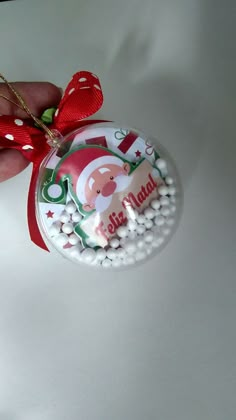 a hand holding a christmas ornament with candy on it's side and a red ribbon