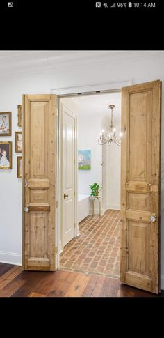 an open door leading to a hallway with pictures on the wall and a potted plant