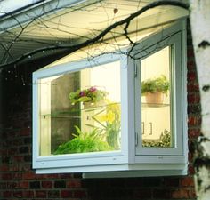 an open window on the side of a brick building with potted plants in it