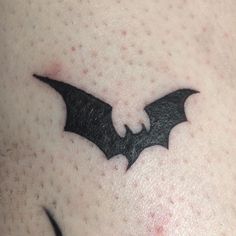 a close up of a person's chest with a bat tattoo on the side