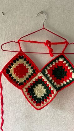 a crocheted red and black bag hanging from a hook on a white wall