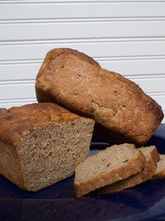 two loaves of bread sit on a blue plate next to another piece of bread