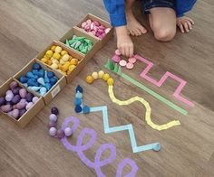 a young child is playing with colored letters on the floor next to boxes of candy