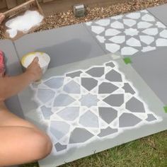 a person painting on the ground with white and gray tiles in front of them,