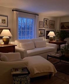 a living room with couches, lamps and pictures on the wall in front of a window