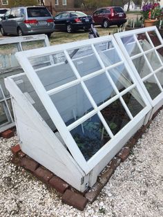 an old greenhouse is being used as a planter in the yard with gravel around it