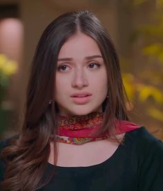 a woman with long hair wearing a red scarf around her neck and looking at the camera