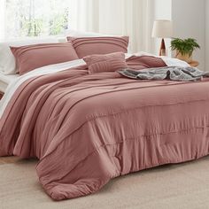 a bed with pink sheets and pillows in a room