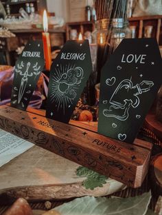 three signs with the words love written on them in front of candles and other items