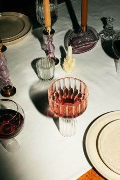 a table topped with glasses and plates covered in wineglasses on top of a white table cloth