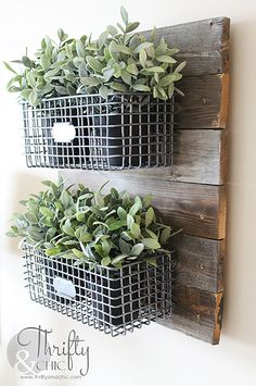 two metal baskets with plants in them hanging on a wall above a sign that says thrift & farmhouse style