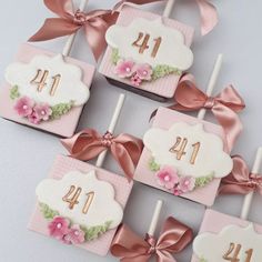 pink and white cake pops decorated with flowers, bows and the number forty one on them