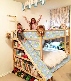 two children are sitting on the bunk bed with their arms in the air and one child is playing