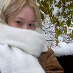 a young woman is wrapped up in a blanket and posing for the camera with snow covered trees behind her