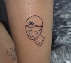 a woman's leg with a tattoo of a man wearing a blindfold and an eye on it