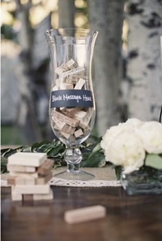 a wine glass filled with lots of corks on top of a table next to flowers