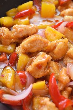 chicken and pineapple stir fry in a pan with onions, peppers, and carrots