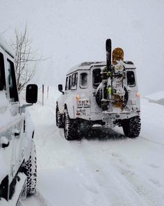 a white truck driving down a snow covered road next to another vehicle in the snow