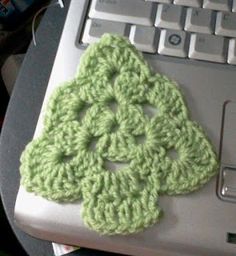 a green crocheted flower sitting on top of a laptop computer's keyboard