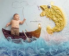 a baby laying on top of a boat next to a fish and a fishing hook