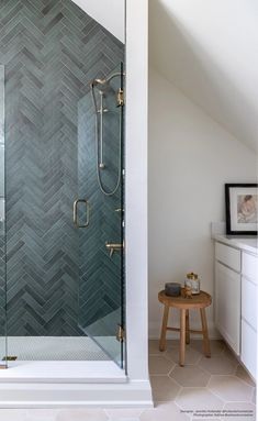 a bathroom with a walk in shower next to a white sink and counter top under a slanted ceiling