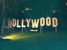 the hollywood sign is lit up at night in front of a building with palm trees