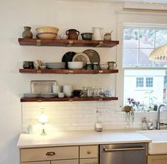 the kitchen is clean and ready to be used for cooking or baking, with dishes on shelves above the sink