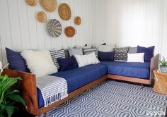 a living room with blue couches and decorative wall hangings on the white walls