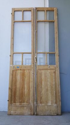 two wooden doors are open on the side of a building in front of a white wall