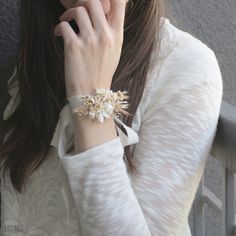 a woman wearing a bracelet with flowers on it and holding her hand to her face