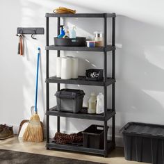 a shelf with various items on it in the corner next to a broom and other cleaning supplies