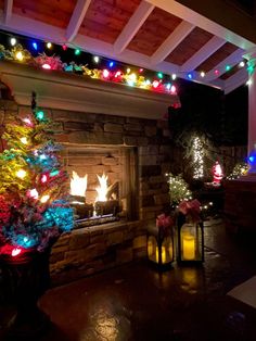 a fireplace with christmas lights on it and a lit tree in the corner next to it