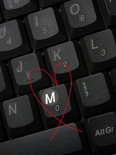 a keyboard with the letter m on it and a red heart in front of it