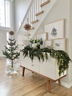 a christmas tree sitting on top of a white dresser next to a stair banister