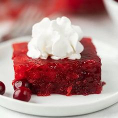 a piece of cake with whipped cream and cherries on top sits on a plate