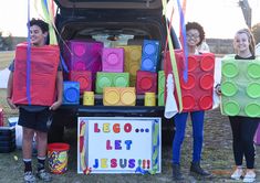 three people standing next to a trunk filled with legos and building blocks on the back of a truck