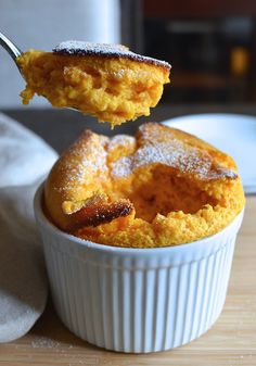 a spoon full of powdered sugar on top of a pastry in a white dish