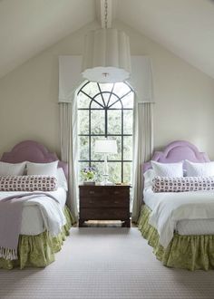 two beds in a room with white walls and windows