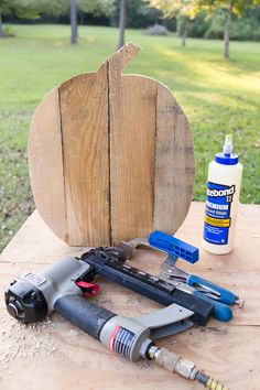 tools are sitting on a table next to a wooden pumpkin shaped object with paint and glue